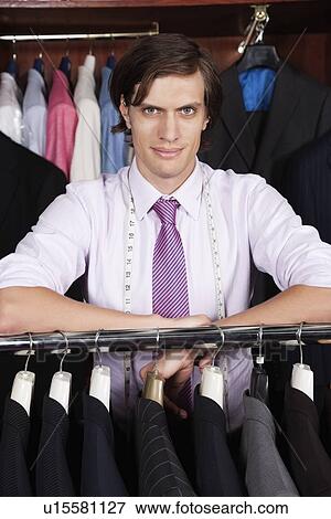 Portrait of confident entrepreneur leaning on clothing rack in store View Large Photo Image Stock Photo - Portrait of confident entrepreneur leaning on clothing rack in store. Fotosearch