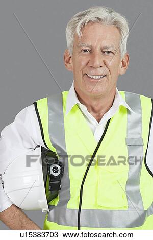Portrait of confident male construction worker with hard hat over gray background View Large Photo Image Stock Image - Portrait of confident male construction worker with hard hat over gray background. Fotosearch