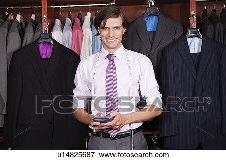Stock Photo - Portrait of confident man with calculator standing against display cabinet. Fotosearch