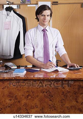 Portrait of confident owner making bills at counter View Large Photo Image Stock Photo - Portrait of confident owner making bills at counter. Fotosearch