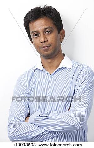 Portrait of confident young Indian man with arms crossed standing against white background View Large Photo Image Stock Image - Portrait of confident young Indian man with arms crossed standing against white background. Fotosearch