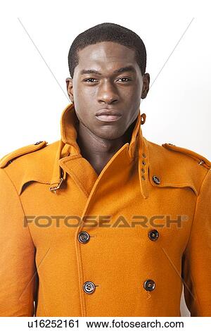 Portrait of confident young man in orange trench coat against white background View Large Photo Image Stock Image - Portrait of confident young man in orange trench coat against white background. Fotosearch