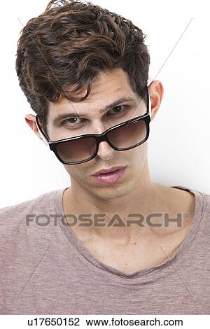 Portrait of confident young man staring against white background View Large Photo Image Stock Image - Portrait of confident young man staring against white background. Fotosearch