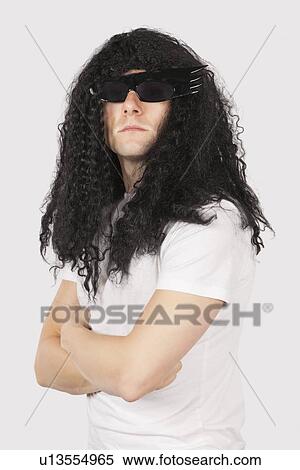 Portrait of confident young man with wig and sunglasses against gray background View Large Photo Image Stock Photography - Portrait of confident young man with wig and sunglasses against gray background. Fotosearch