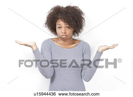 Stock Photograph - Portrait of confused African American young woman shrugging against white background. Fotosearch
