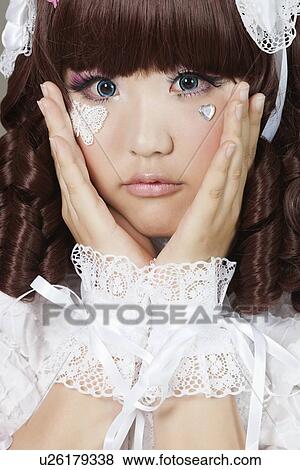 Stock Photo - Portrait of cute young woman in doll costume over gray background. Fotosearch
