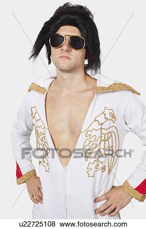 Portrait of Elvis impersonator in white jump suit with hands on hips against gray background View Large Photo Image Stock Photo - Portrait of Elvis impersonator in white jump suit with hands on hips against gray background. Fotosearch