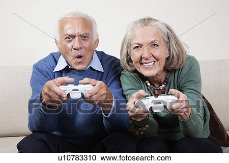 Portrait of excited senior couple playing video game at home View Large Photo Image Stock Image - Portrait of excited senior couple playing video game at home. Fotosearch