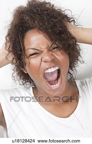 Portrait of frustrated young woman with hands in hair screaming against white background View Large Photo Image Picture - Portrait of frustrated young woman with hands in hair screaming against white background. Fotosearch