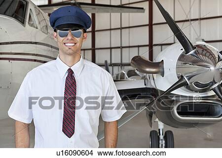 Portrait of handsome young pilot standing in front of airplane View Large Photo Image Picture - Portrait of handsome young pilot standing in front of airplane. Fotosearch