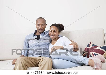 Portrait of happy African American young couple relaxing on sofa View Large Photo Image Picture - Portrait of happy African American young couple relaxing on sofa. Fotosearch