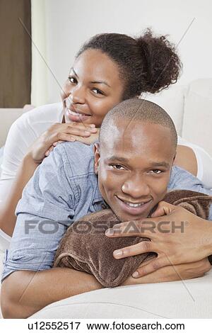Portrait of happy African American young couple relaxing on sofa View Large Photo Image Stock Photo - Portrait of happy African American young couple relaxing on sofa. Fotosearch