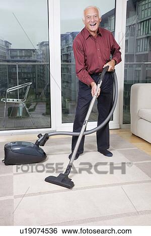 Portrait of happy elderly man cleaning rug with vacuum cleaner at home View Large Photo Image Stock Photograph - Portrait of happy elderly man cleaning rug with vacuum cleaner at home. Fotosearch