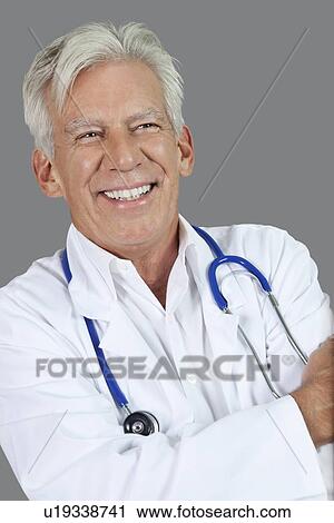 Portrait of happy senior male doctor over gray background View Large Photo Image Stock Image - Portrait of happy senior male doctor over gray background. Fotosearch