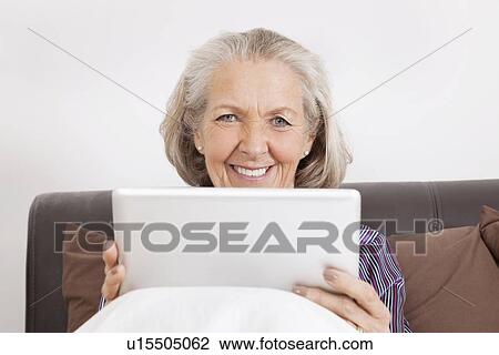 Stock Image - Portrait of happy senior woman with digital tablet at home. Fotosearch