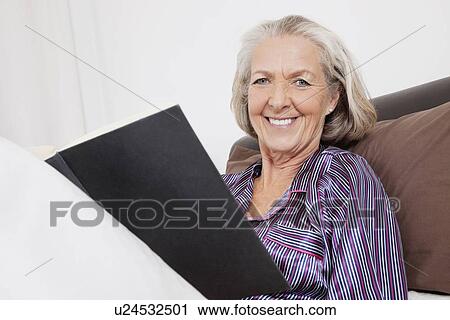 Portrait of happy senior woman with book sitting at home View Large Photo Image Stock Image - Portrait of happy senior woman with book sitting at home. Fotosearch