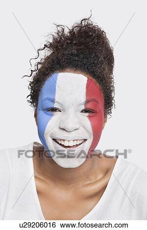 Stock Photograph - Portrait of happy young African American woman with French flag painted on face against white background. Fotosearch