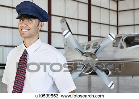 Portrait of happy young male pilot standing in front of airplane View Large Photo Image Stock Image - Portrait of happy young male pilot standing in front of airplane. Fotosearch