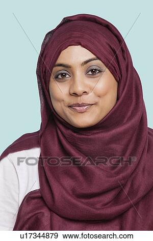 Portrait of happy young Muslim woman in traditional clothing against blue background View Large Photo Image Stock Photo - Portrait of happy young Muslim woman in traditional clothing against blue background. Fotosearch