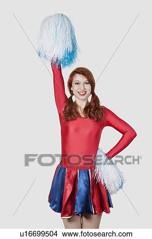 Portrait of happy young woman in cheer leader costume standing against gray background View Large Photo Image Picture - Portrait of happy young woman in cheer leader costume standing against gray background. Fotosearch