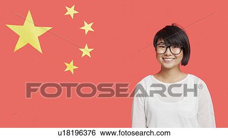 Stock Photograph - Portrait of happy young woman wearing eyeglasses against Chinese flag. Fotosearch