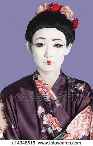 Stock Photography - Portrait of Japanese woman in kimono with painted face against purple background. Fotosearch