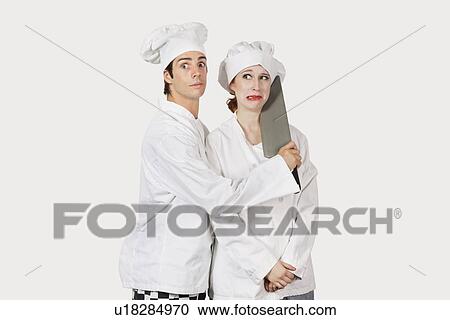 Portrait of male chef attacking female colleague with a cleaver against gray background View Large Photo Image Stock Image - Portrait of male chef attacking female colleague with a cleaver against gray background. Fotosearch