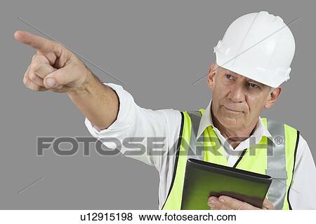 Portrait of male construction worker with tablet PC pointing over gray background View Large Photo Image Stock Photo - Portrait of male construction worker with tablet PC pointing over gray background. Fotosearch