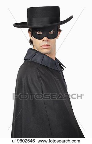 Stock Photograph - Portrait of man dressed as Zorro over gray background. Fotosearch