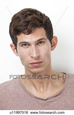 Portrait of serious young man against white background View Large Photo Image Stock Photograph - Portrait of serious young man against white background. Fotosearch
