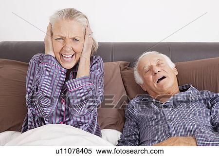 Portrait of shocked sitting with husband sleeping on bed at home View Large Photo Image Stock Photography - Portrait of shocked sitting with husband sleeping on bed at home. Fotosearch