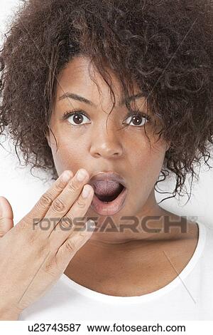 Stock Photo - Portrait of shocked young African American woman with hand over mouth. Fotosearch