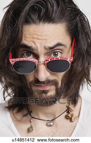 Portrait of suspicious young man wearing sunglasses against white background View Large Photo Image Stock Image - Portrait of suspicious young man wearing sunglasses against white background. Fotosearch