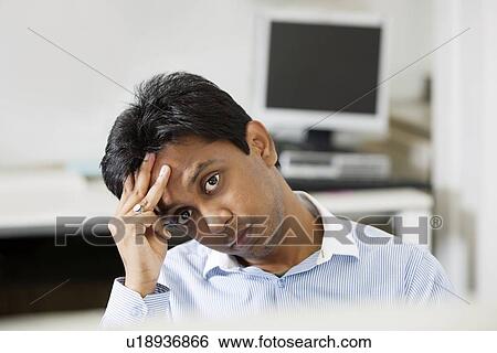 Portrait of tensed young businessman with hand on head at office View Large Photo Image Stock Photograph - Portrait of tensed young businessman with hand on head at office. Fotosearch