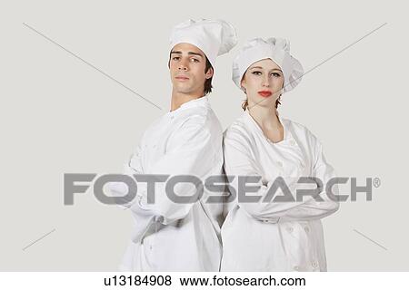 Stock Photo - Portrait of two confident chefs with arms crossed against gray background. Fotosearch