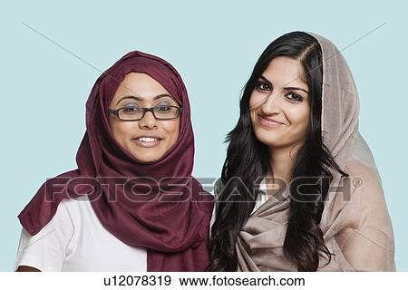 Portrait of two happy young Muslim women in traditional clothing against blue background View Large Photo Image Stock Photo - Portrait of two happy young Muslim women in traditional clothing against blue background. Fotosearch