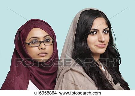 Portrait of two young Muslim women in traditional clothing against blue background View Large Photo Image Picture - Portrait of two young Muslim women in traditional clothing against blue background. Fotosearch