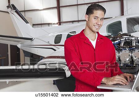 Portrait of young aeronautic engineer using laptop in front of airplane View Large Photo Image Stock Image - Portrait of young aeronautic engineer using laptop in front of airplane. Fotosearch
