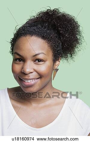 Picture - Portrait of young African American woman smiling against green background. Fotosearch