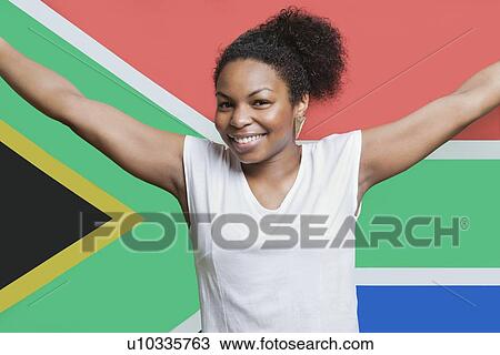 Stock Image - Portrait of young African American woman smiling against South African flag. Fotosearch