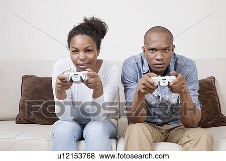 Portrait of young African American couple playing video game View Large Photo Image Stock Photo - Portrait of young African American couple playing video game. Fotosearch