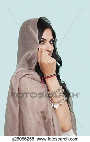 Portrait of young Asian woman in traditional clothing holding dupatta against blue background View Large Photo Image Stock Photo - Portrait of young Asian woman in traditional clothing holding dupatta against blue background. Fotosearch
