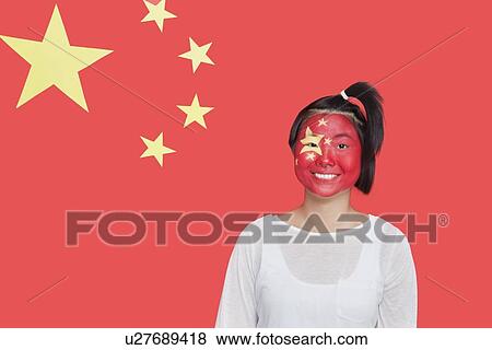 Stock Photo - Portrait of young Asian woman with painted face smiling against Chinese flag. Fotosearch
