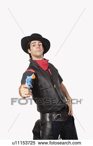 Portrait of young cowboy aiming handgun against gray background View Large Photo Image Stock Photography - Portrait of young cowboy aiming handgun against gray background. Fotosearch