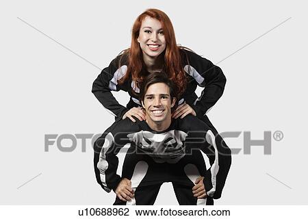 Portrait of young man giving piggyback ride in skeleton costume over gray background View Large Photo Image Stock Image - Portrait of young man giving piggyback ride in skeleton costume over gray background. Fotosearch