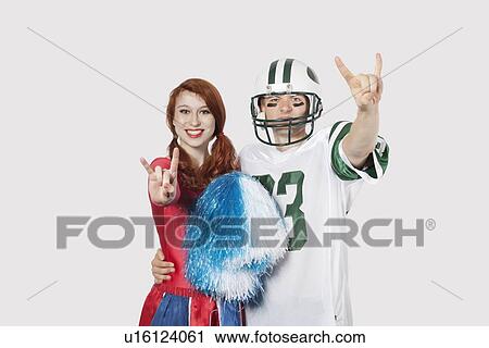 Portrait of young man in football uniform and cheerleader gesturing over gray background View Large Photo Image Stock Image - Portrait of young man in football uniform and cheerleader gesturing over gray background. Fotosearch