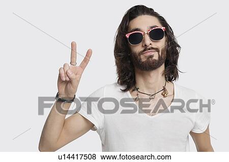 Portrait of young man wearing sunglasses gestures peace sign against white background View Large Photo Image Stock Photo - Portrait of young man wearing sunglasses gestures peace sign against white background. Fotosearch