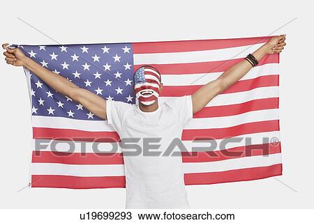 Stock Image - Portrait of Young man with American flag and painted face against white background. Fotosearch