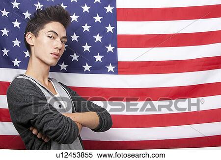 Portrait of young man with arms crossed standing against American flag View Large Photo Image Stock Photography - Portrait of young man with arms crossed standing against American flag. Fotosearch