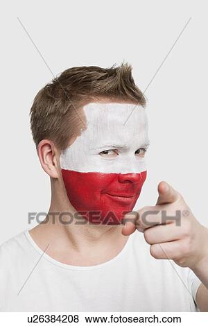 Portrait of young man with Polish flag painted on face pointing finger against white background View Large Photo Image Stock Photo - Portrait of young man with Polish flag painted on face pointing finger against white background. Fotosearch